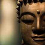 A close up of a bronze Buddah's face.